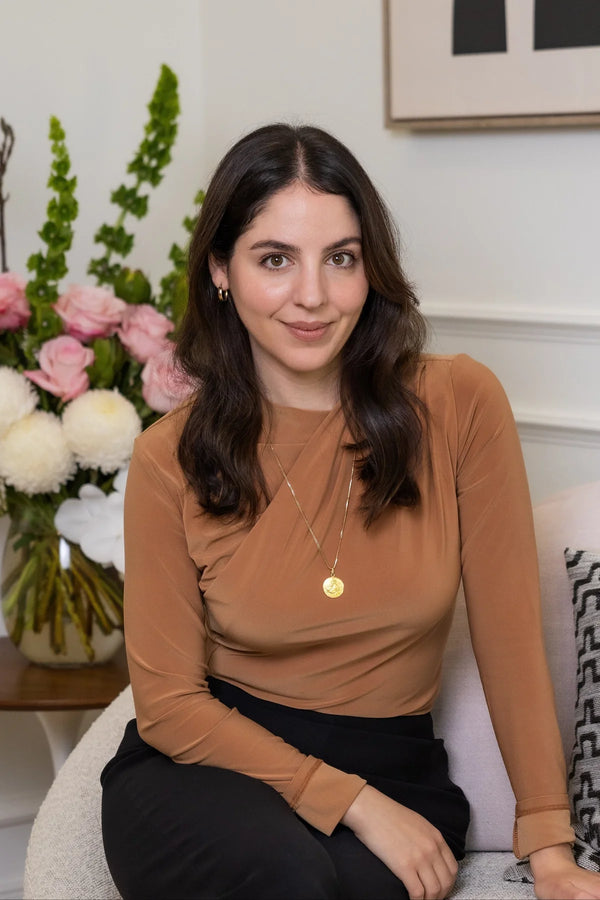 Woman sitting on a couch with flowers and a painting in the background