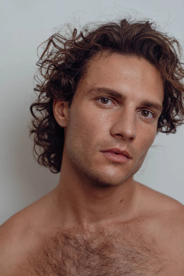 Man with curly hair and a light background