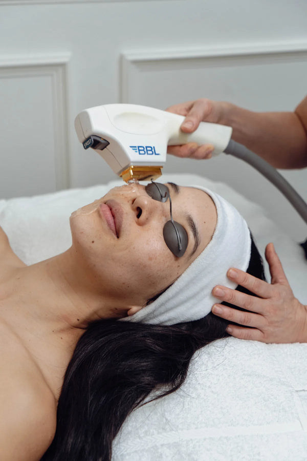 Woman receiving a facial treatment with a device labeled 'BBL' on a white background.