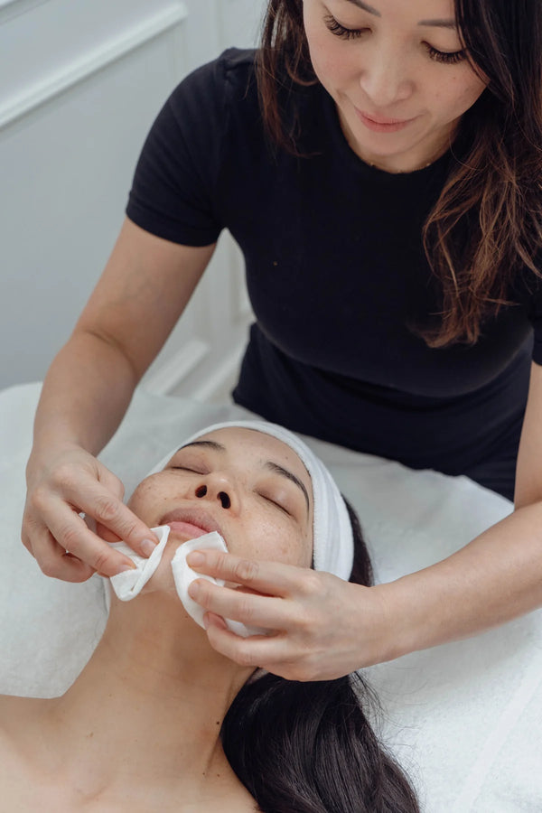 Person receiving a facial treatment with a professional in a clinical setting.