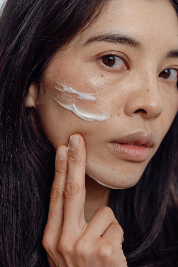 Woman applying cream to her face 