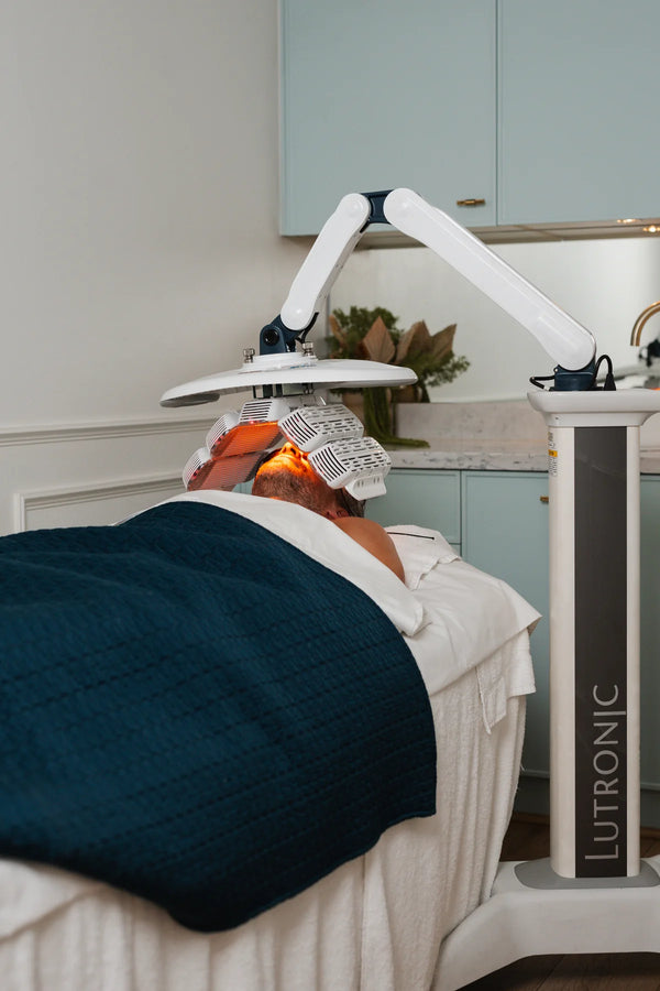 Person receiving a treatment under a Lutronic LED light therapy device in a clinical setting.