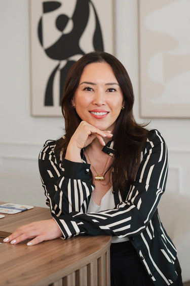 Woman in a black and white striped shirt sitting at a desk with abstract art in the background