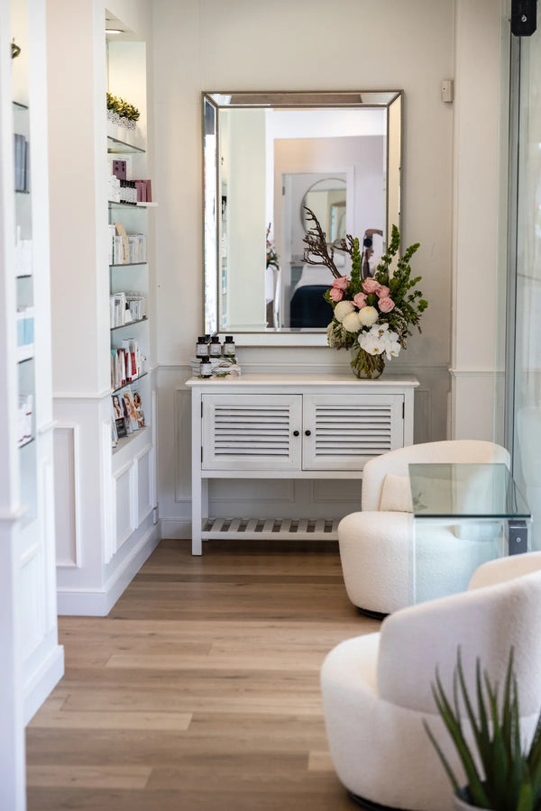 Modern interior with white furniture, a mirror, and decorative plants.
