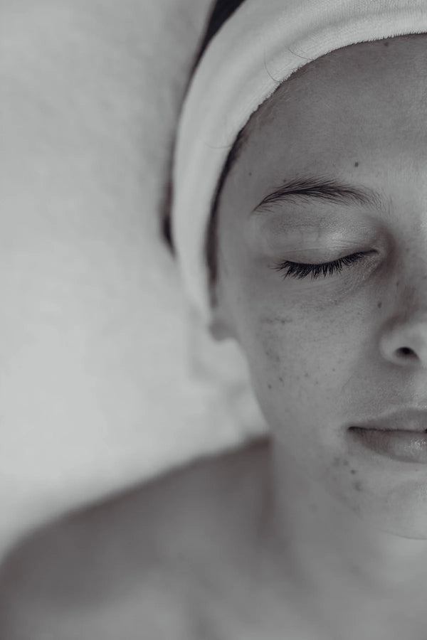 Close-up of a person with a towel on their head against a plain background